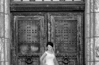 Der Hochzeitsfotograf in Hannover, Michael Siebert, setzt Braut allein vor Kirchentuer, schwarz weiß in Szene.